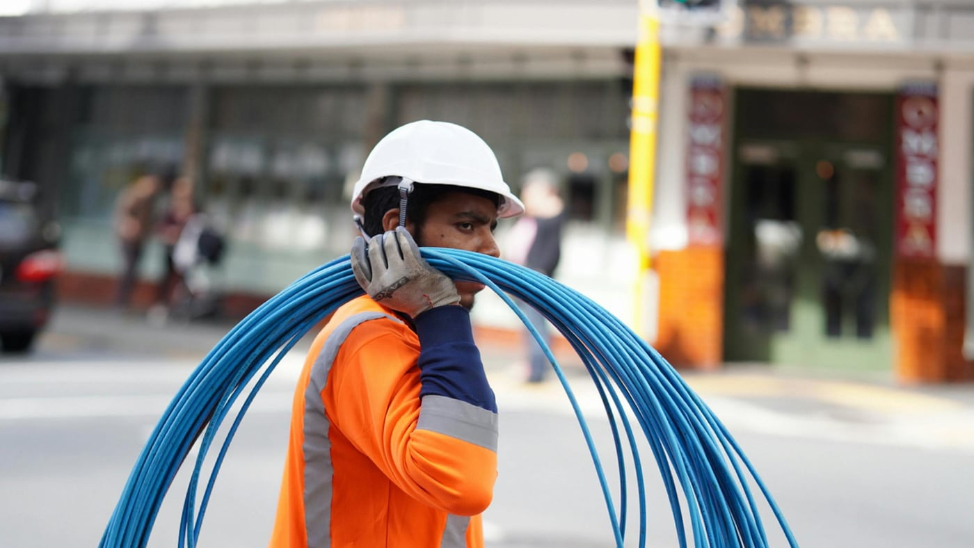 Technician carrying a coil of blue fibre cable on site